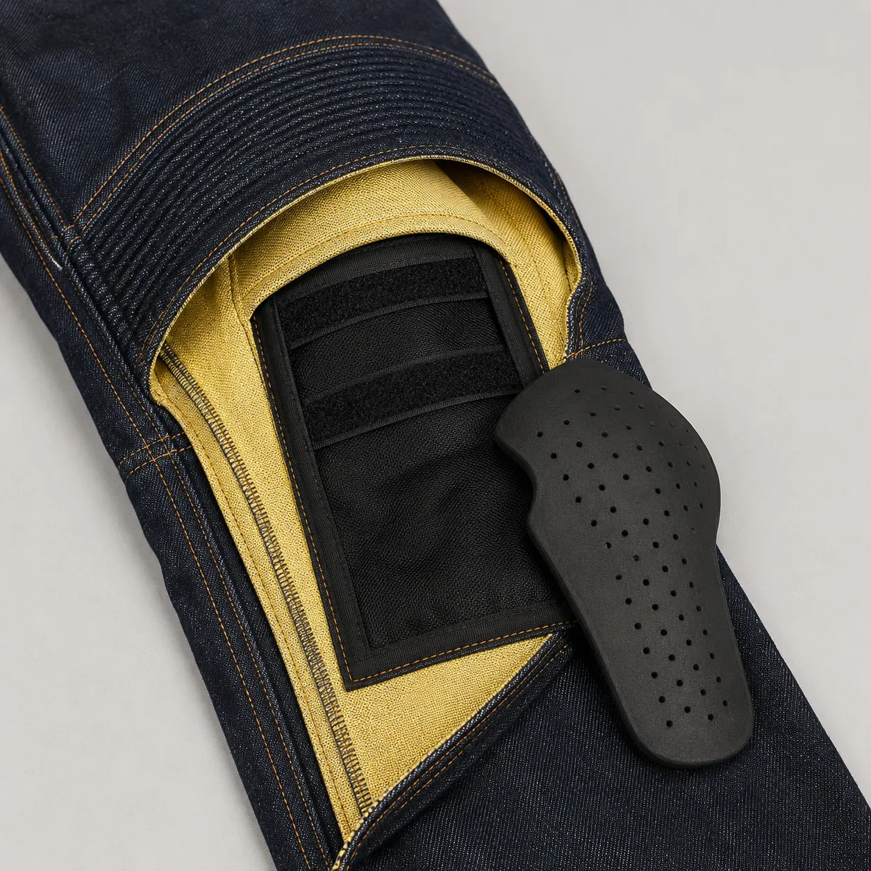 Motorcycle jeans leg opened to show an adjustable internal knee pad pocket and removable knee pad